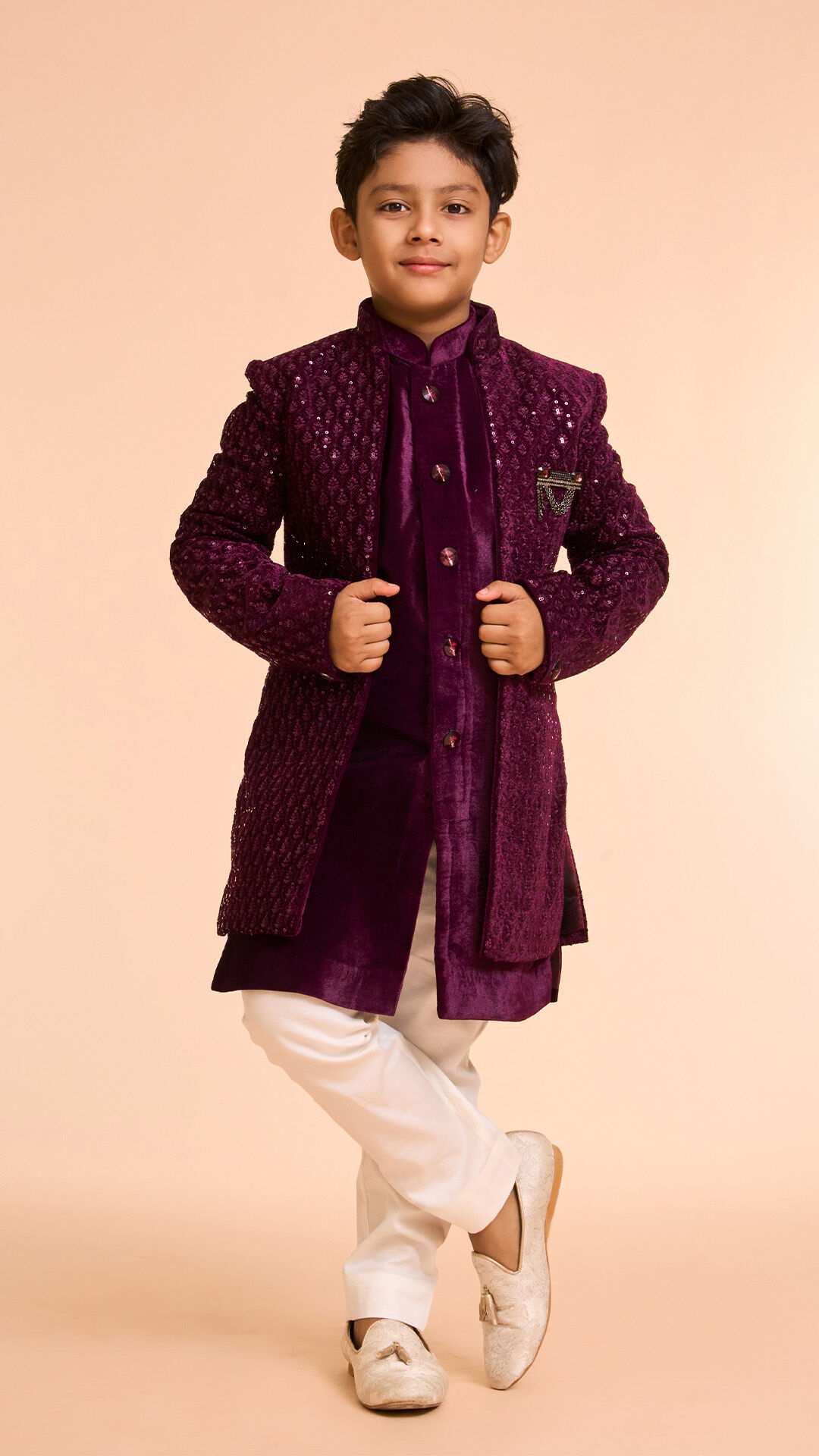 A boy wearing a Red angrakha jacket outfit for wedding celebration